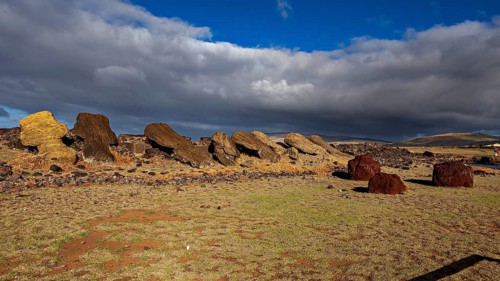 Fallen moai lie on a rocky area under a cloudy sky, the moai statues on Easter Island in the