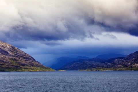 Dramatic scene with mountains and sea under a stormy cloudy sky, coordinates: 51°49'58.83 S,
