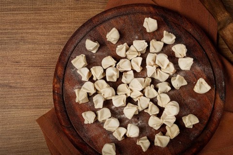 Traditional Turkish dumplings, raw, on a cutting board, top view, no people