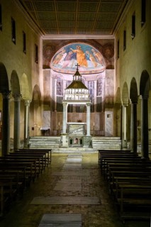 Interior view through central nave of altar and apse in three-nave flat-roofed columned basilica