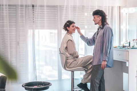 Professional makeup artist carefully applying makeup on a client's face, enhancing her natural