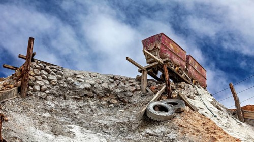 Two abandoned wagons stand on a hill under a blue sky, The Potosi Silver Mines on Cerro Rico in