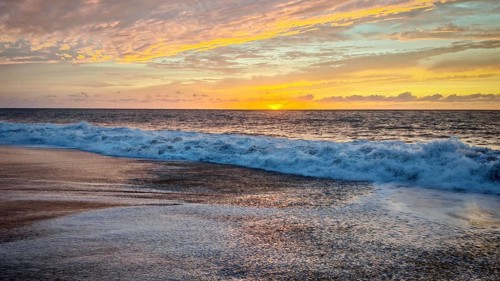 Soft waves on the beach at sunset with orange sky over the sea, Tarrafal de Monte Trigo, Santo