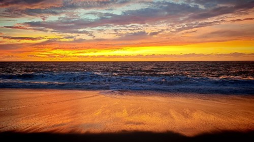Romantic, calm sunset on the beach with intense orange tones on the horizon and light waves,