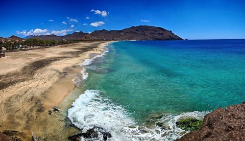 View from above of vast coastal landscape with transparent water and gentle waves on a sandy beach,