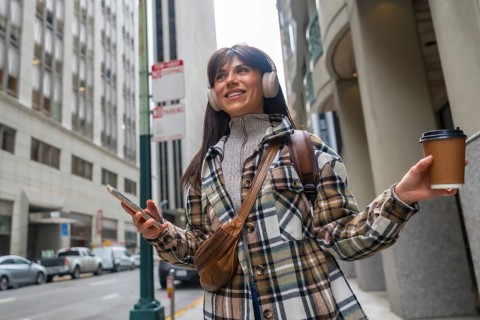Young woman walking outdoors in downtown san francisco, wearing a plaid jacket and headphones,