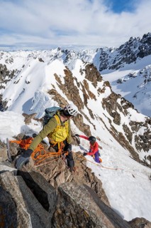 Mountaineer belaying on a steep snow slope, belaying on a rope, ascent to the summit of Piz