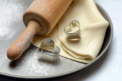 Rolled dough on cake tray with dough rollers and cookie cutters