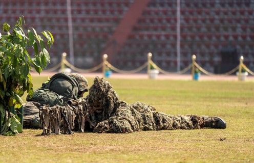 A camouflaged sniper of the Central Reserve Police Force takes aim during a tactical demonstration