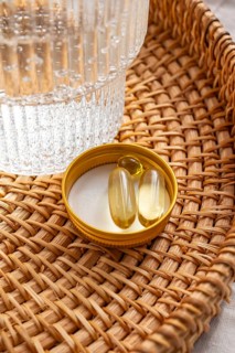 Close-up view of Omega 3 fish oil capsules and Vitamin D3 placed in a yellow lid on a decorative