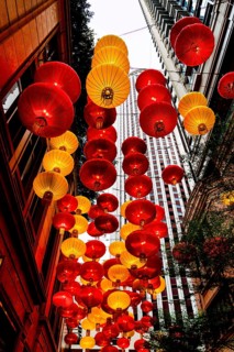 From below radiant red and yellow lanterns hang between skyscrapers in Hong Kong, celebrating