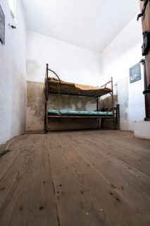 Simple room with bunk bed, wooden floor and white walls, looks spartan and plain, Prison Museum,