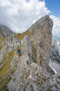 Mountaineers on a narrow hiking trail on a rocky ridge, ascent to the Maukspitze, clouds moving