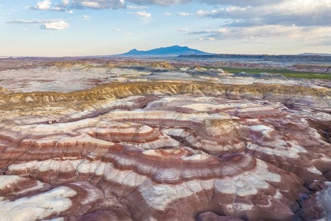 Captivating aerial shot of layered bentonite hills with unique erosion patterns and distant