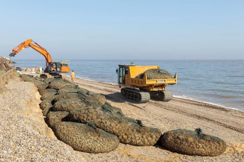 Emergency coastal defences work placing rock bags on beach to protect property, North Sea coast,