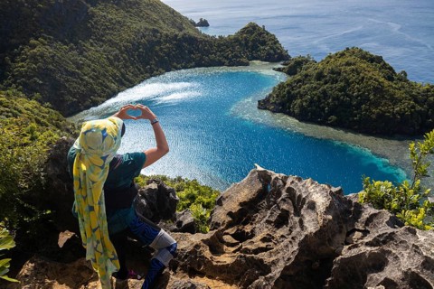 An ecotourist admires the breathtaking view of crystal-clear blue waters and lush green islands in