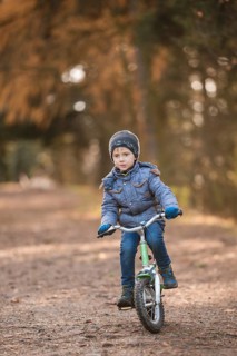Six years old boy rides bicycle from the hill in the park