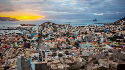 Panoramic view from above of coastal town of Mindelo at sunset with colorful buildings, harbor and