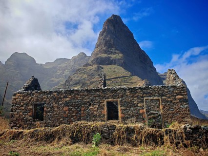 Volcanic stone ruin in front of a high mountain, sky with few clouds, hiking, lost place, abandoned