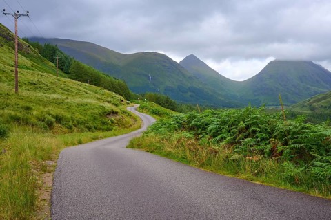 Winding road through a green valley surrounded by mountains under a cloudy sky, Loch Etive, Argyll