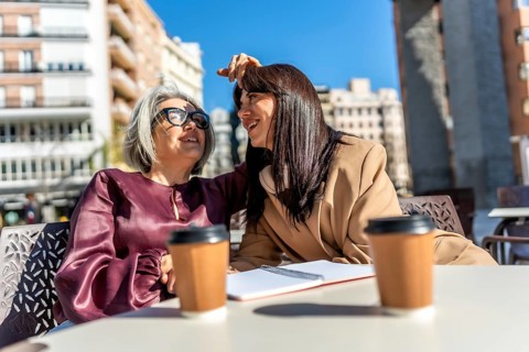 Two women friends sharing an authentic moment of connection and discussion at an outdoor cafe in