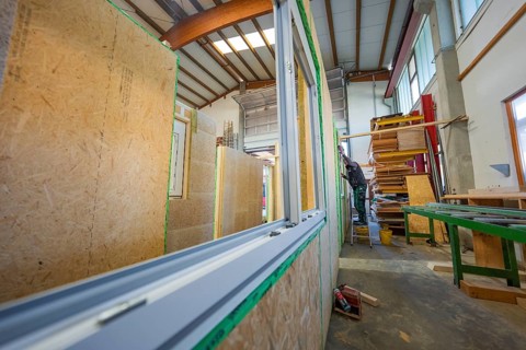 Construction of wooden walls in a workshop, window assembled, structured work environment, façade