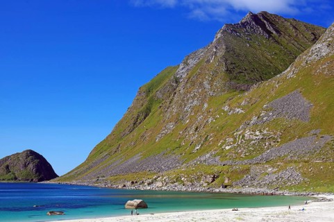 A long beach in front of towering mountains under clear skies, Haukland, Leknes, Vestvågøya,