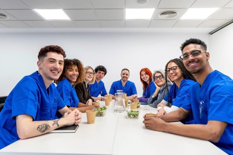 Diverse healthcare professionals wearing scrubs and business casual attire smiling at the camera