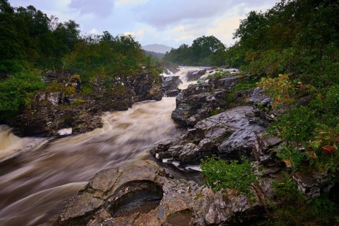 An impressive river with fast currents, lined with trees, under a cloudy sky, River Orchy, Eas