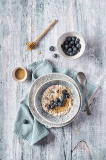 Overhead delicious fresh overnight oats porridge with blueberries and cream on kitchen towel on