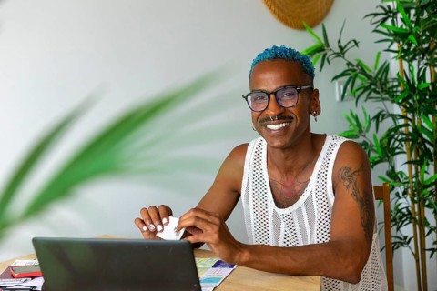 A joyful LGBTQIA+ individual with blue hair and glasses is preparing for holidays at home,