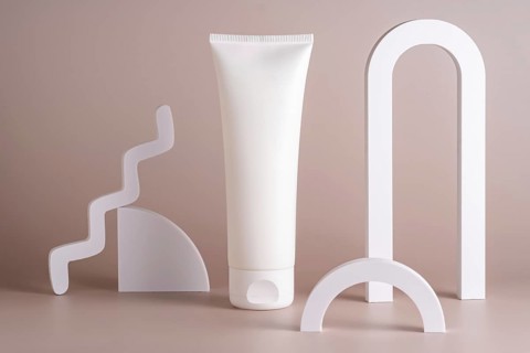 A minimalist skincare concept featuring a white tube surrounded by sleek geometric shapes on a