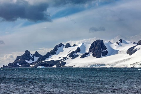 Snow-covered coastal mountains that stand out dramatically against the blue sky, The landscape in
