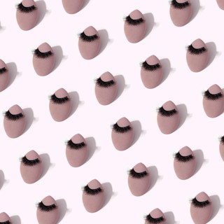 A seamless pattern featuring makeup sponges adorned with false eyelashes set against a soft