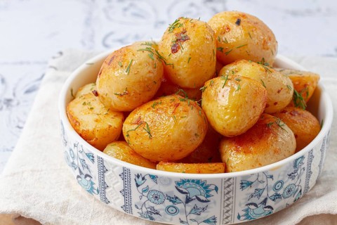 Baked new potatoes, with butter and dill, on a white plate, at home, no people