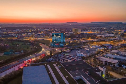 City panorama with a high-rise building at sunset and evening lights, Porsche, Bietigheim, Germany