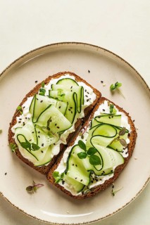 Breakfast, cereal bread sandwiches, cream cheese, sliced cucumber, with micro greenery on a light