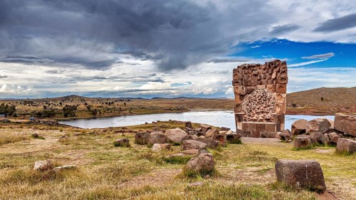Stone ruin in a grassy landscape with a view of lake and sky, The Chullpas of Sillustani near Puno
