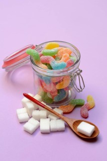 Lots of colorful jelly sweets in glass containers and sugar cubes, sugar consumption