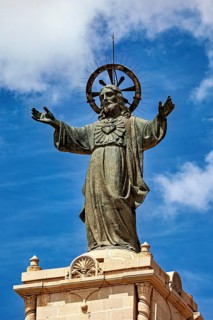 Large statue of Jesus with outstretched arms and halo against a blue sky, The Jesus statue of