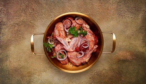 Chicken wings, in a brass saucepan, ready for cooking, grilling or baking, in a home kitchen, no
