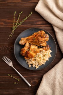 Fried Turkey Wing with spices and thyme on plate on brown wooden background and linen textile. top