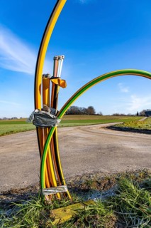 Fibre optic connection, empty conduits protrude from the ground along a dirt track, into which the