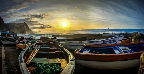 Colourful fishing boats rest on the shore in the soft light of an evening sunset, romantic harbor