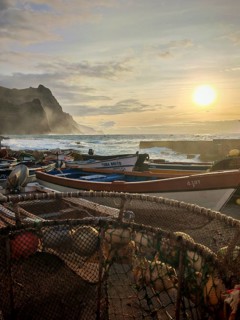 Fishing boats and nets against a picturesque coastal landscape at sunset, Ponta do Sol, Santo