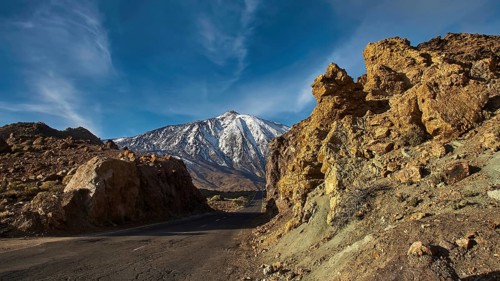 An asphalted road between rocky slopes in a mountainous area under blue sky, Teide, Parque Nacional