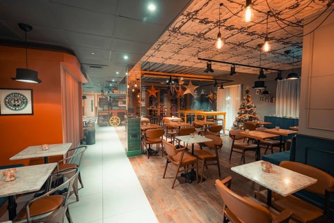 Contemporary industrial-style restaurant with warm lighting, wooden decor and Christmas tree, Ibis