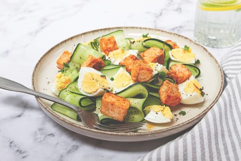 Delicious salmon and egg salad served on a plate with fresh cucumber and herbs for a healthy meal