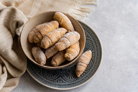 Top view of a rustic bowl filled with homemade croissants, dusted lightly with flour, on a
