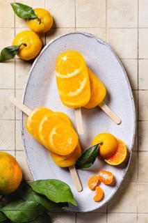 Top view of a refreshing tangerine flavored ice pops displayed on a rustic ceramic plate,